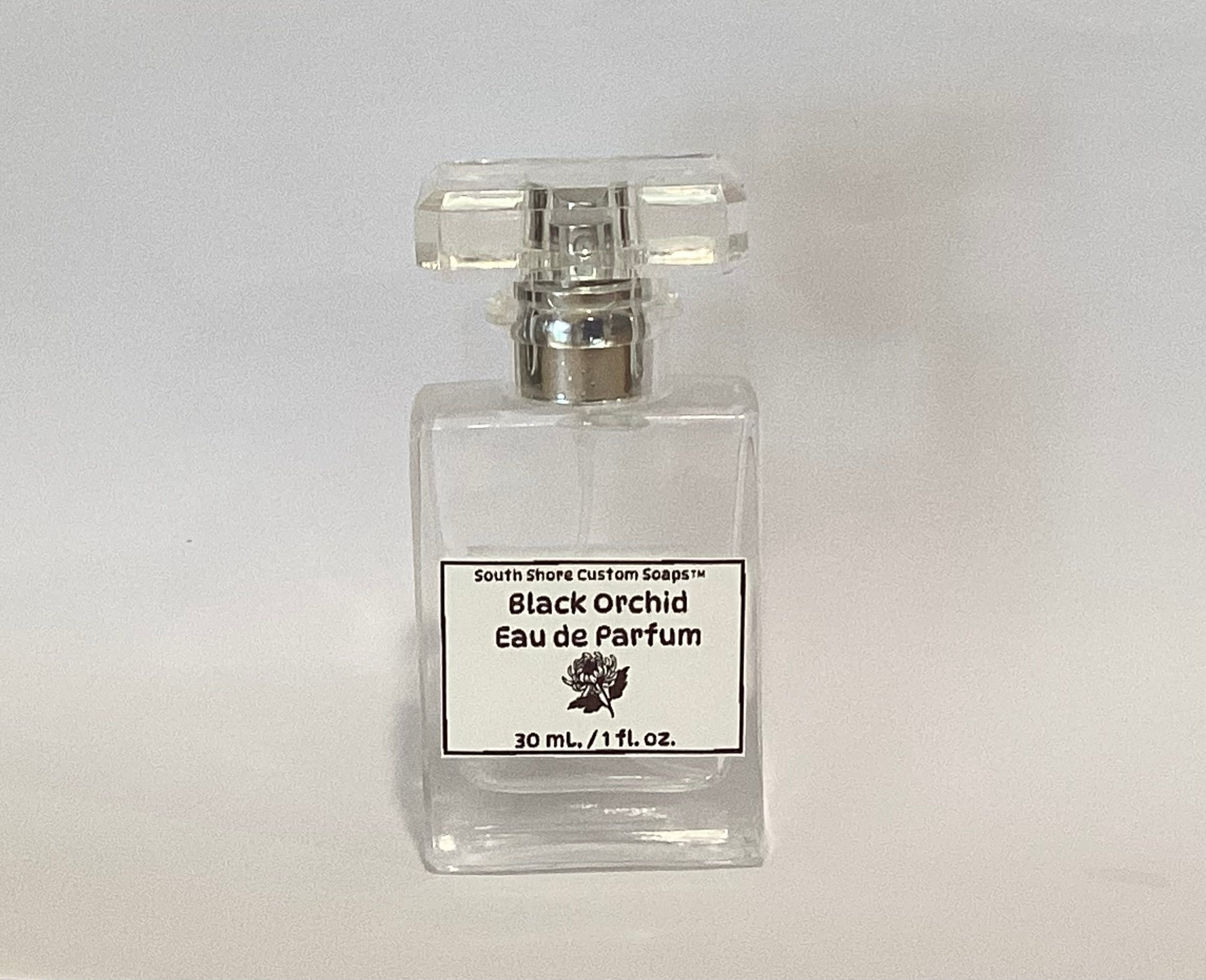 A clear glass perfume bottle with a silver atomizer and a white label reading 'Black Orchid Eau de Parfum' by South Shore Custom Soaps, set against a plain light gray background.